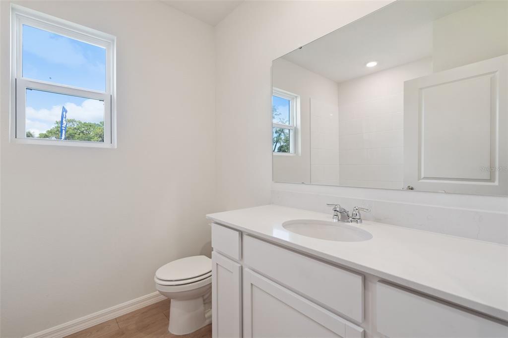 A bathroom features a white vanity with a single sink, a toilet, and a mirror — 2514 DORSET COURT, ORMOND BEACH, FL