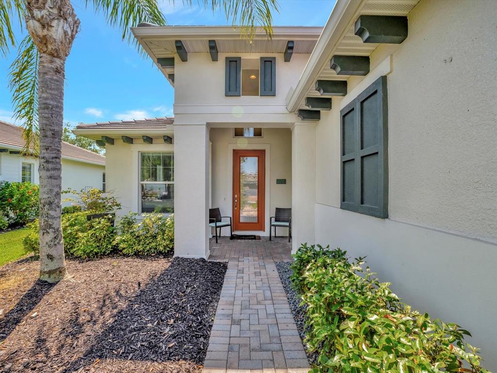 A paved walkway leads to the front entrance of a house with a wooden door — 5009 LAKE OVERLOOK AVENUE, BRADENTON, FL