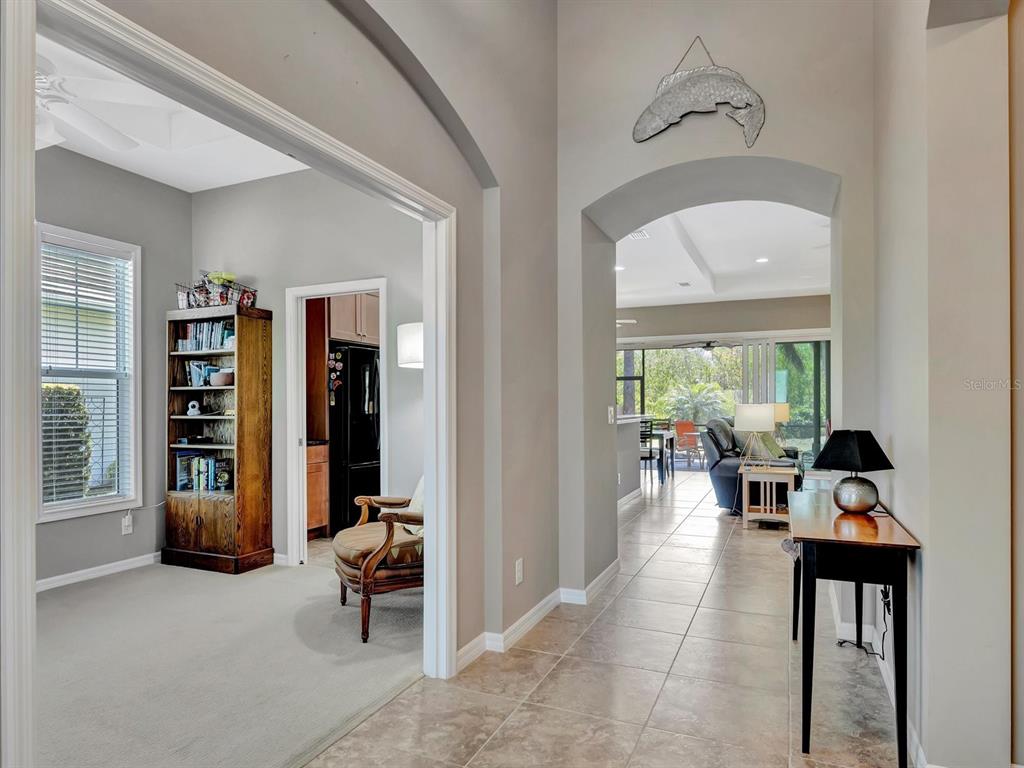 A hallway with tile flooring leads to a living area with a view of a patio — 5009 LAKE OVERLOOK AVENUE, BRADENTON, FL