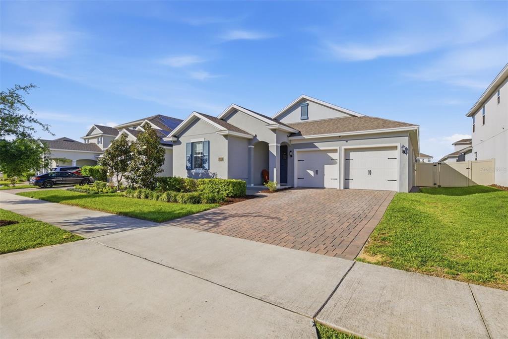 A single-story gray house features a blue front door, blue shutters, and a paved driveway — 15033 LAKE BESSIE LOOP, WINTER GARDEN, FL