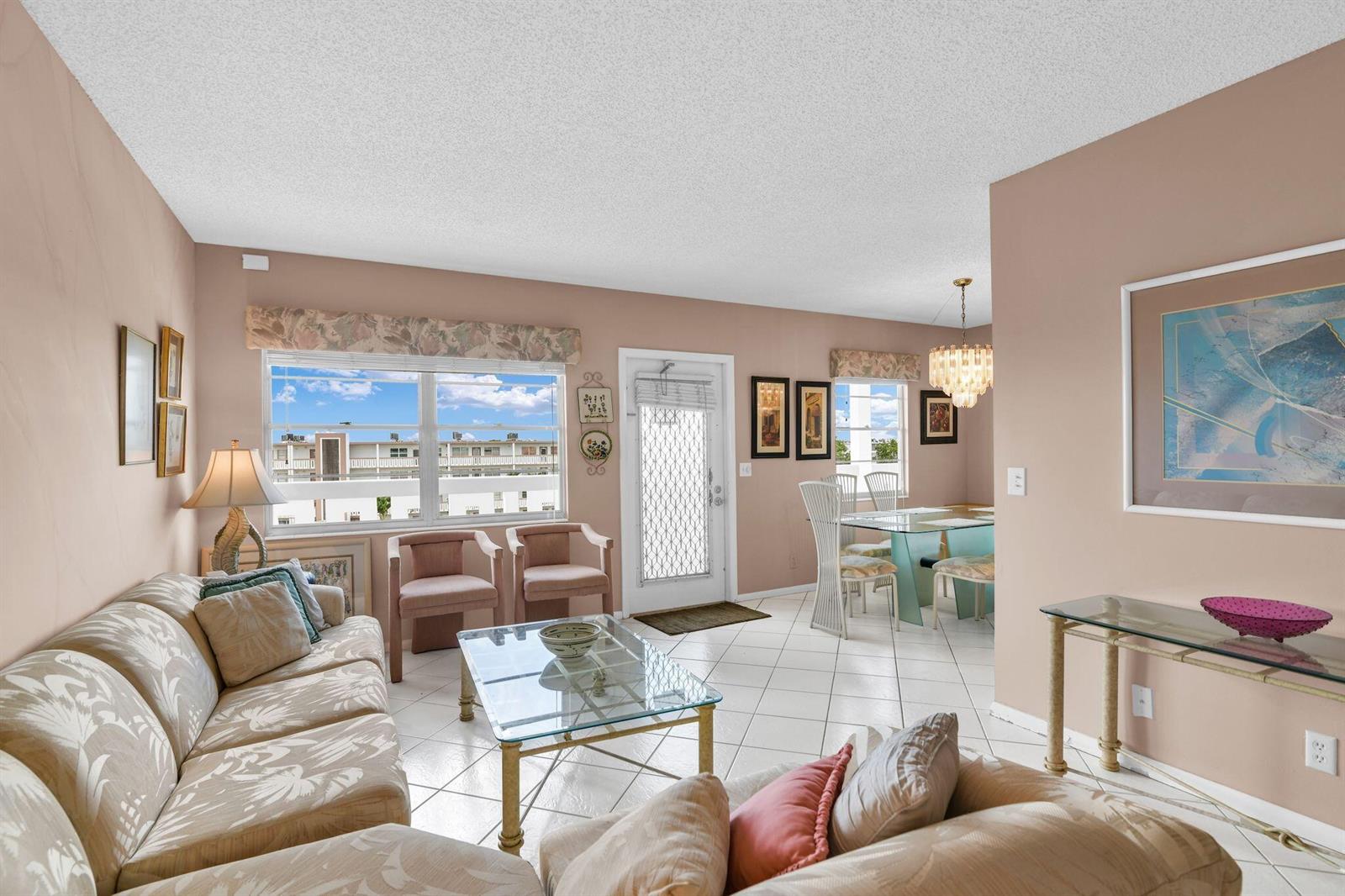 A living and dining area with tile floors, a glass coffee table, and large windows — 4053 Wolverton C, Boca Raton FL 33434, BOCA RATON, FL