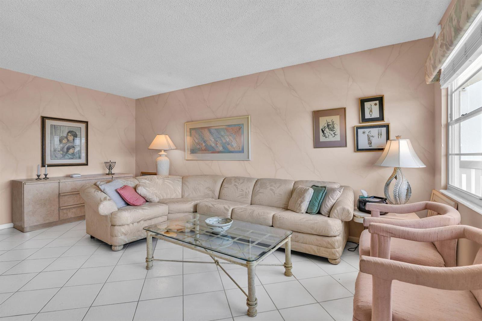 A living room features a beige sectional sofa, glass coffee table, and pink upholstered chairs — 4053 Wolverton C, Boca Raton FL 33434, BOCA RATON, FL