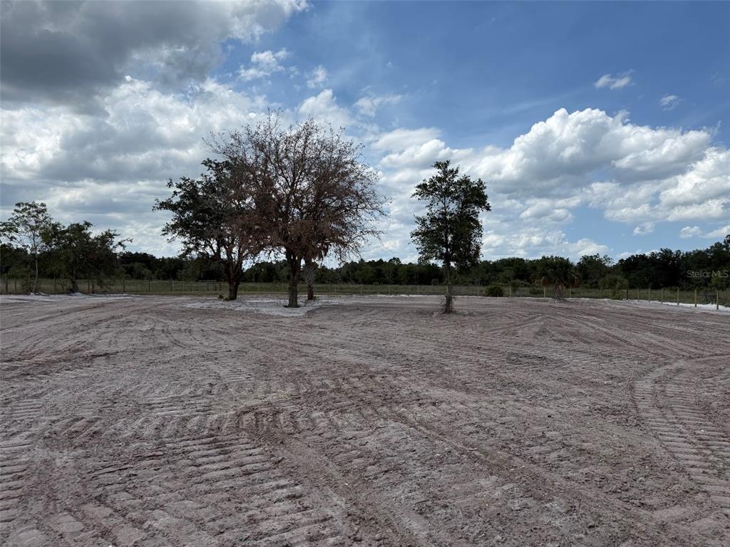 A cleared, sandy lot features several trees under a blue sky with scattered clouds — 14667 NW 310TH STREET, OKEECHOBEE, FL