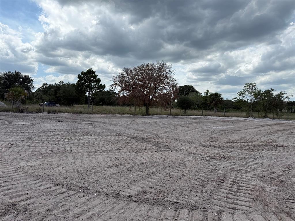 A large, cleared dirt lot features tire tracks and a wire fence with trees behind — 14667 NW 310TH STREET, OKEECHOBEE, FL