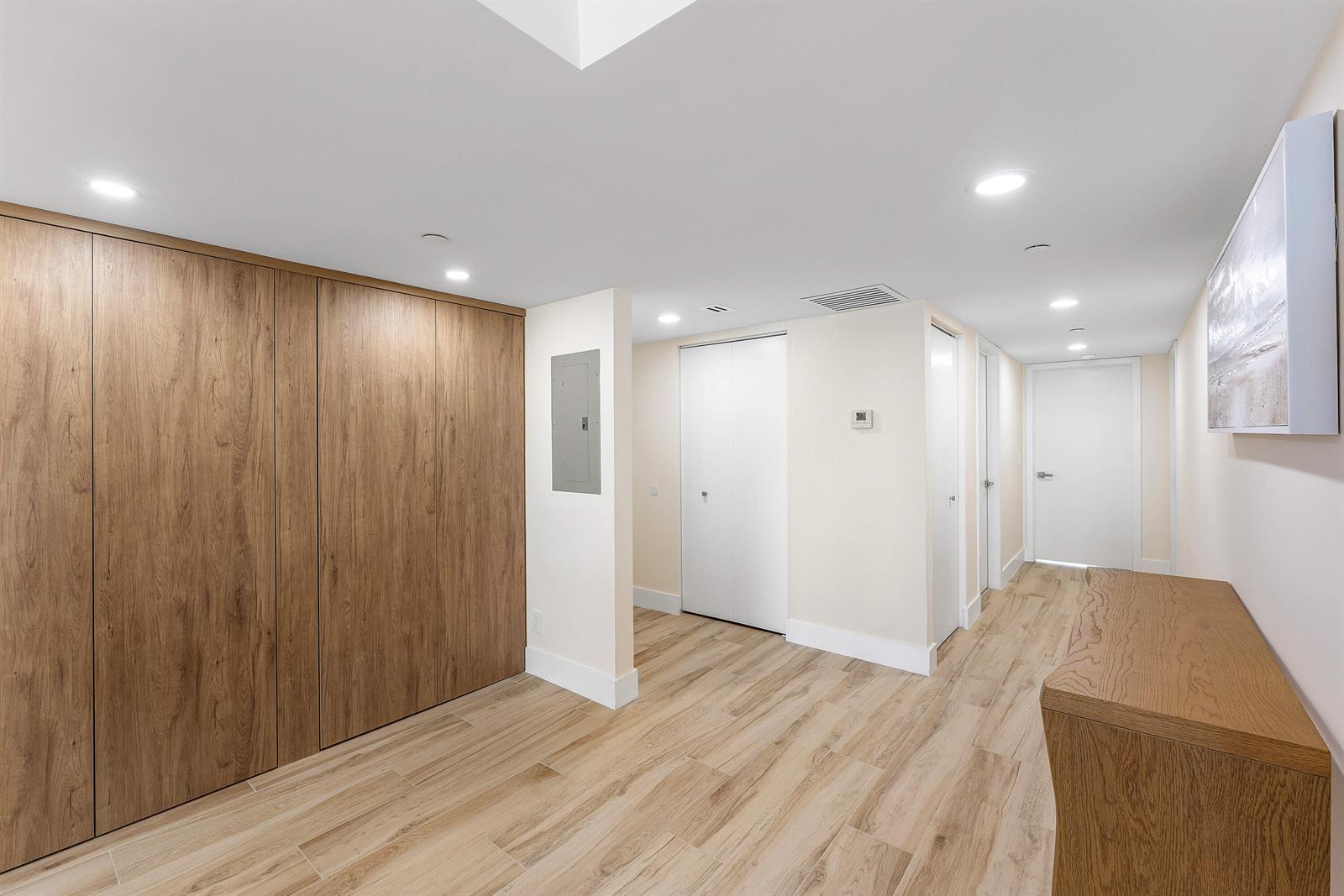 A hallway features wood-paneled walls, light wood flooring, recessed lighting, and several white doors — 4201 N Ocean Boulevard # 1407, Boca Raton FL 33431, BOCA RATON, FL
