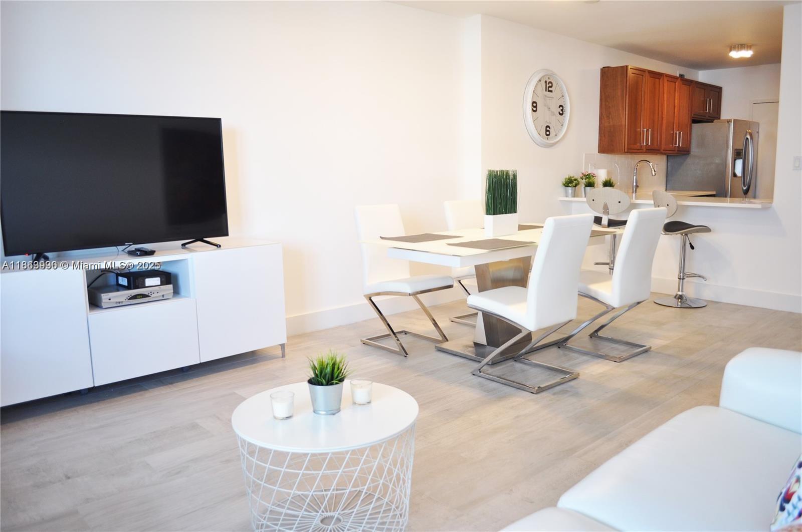 A living and dining area features a white media console, dining table, and kitchen bar — 100 Lincoln Rd # 435, Miami Beach FL 33139, MIAMI BEACH, FL
