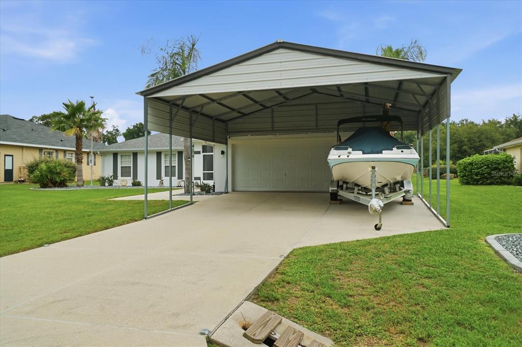A metal carport covers a concrete driveway and a boat parked in front of a house — 4457 E AVOCET COURT, INVERNESS, FL