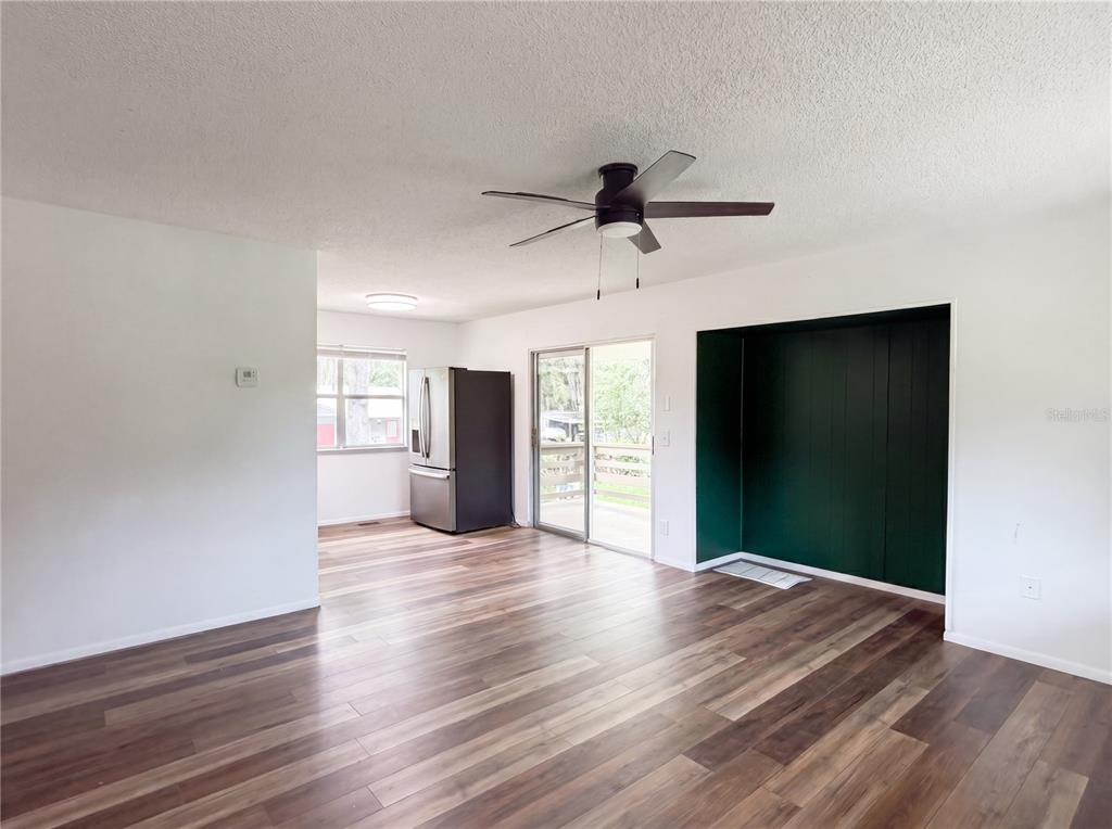 A living room with wood-look flooring, a ceiling fan, and a dark green accent wall — 22415 HORIZON VISTAS DRIVE, EUSTIS, FL