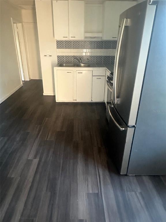 A kitchen features white cabinets, a stainless steel refrigerator, and dark wood-look flooring — 1611 INDIAN TRAIL, LEESBURG, FL
