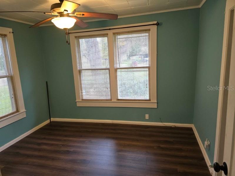 An empty room with teal walls, dark wood-look flooring, and a ceiling fan — 1611 INDIAN TRAIL, LEESBURG, FL