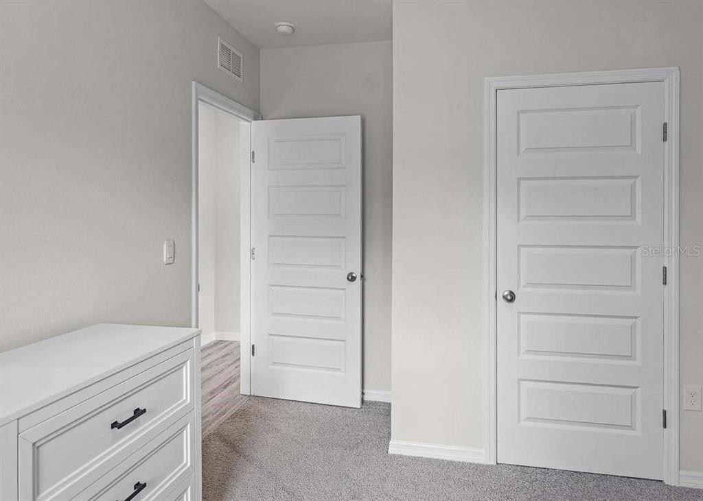 A white dresser sits in a room with gray carpet, white walls, and two doors — 2934 PENNACHIO DRIVE, LAKE WALES, FL