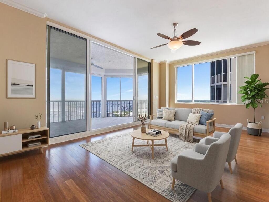 A living room with hardwood floors, a ceiling fan, and large windows overlooking a balcony — 2104 W FIRST STREET UNIT 2304, FORT MYERS, FL