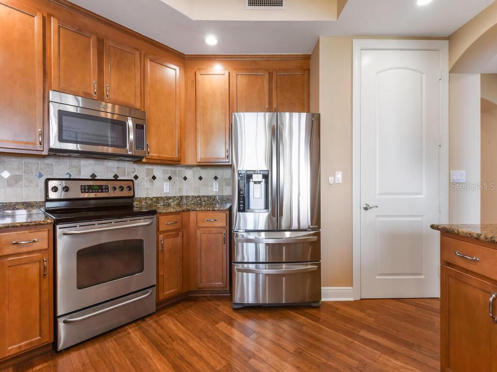A kitchen features wood cabinets, stainless steel appliances, granite countertops, and hardwood flooring — 2104 W FIRST STREET UNIT 2304, FORT MYERS, FL