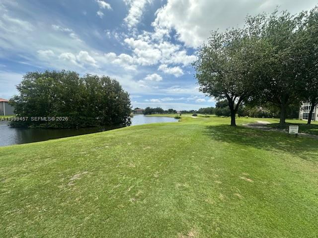 A grassy lawn leads to a pond surrounded by trees under a cloudy sky — 2420 SW 81st Ave # 403, Davie FL 33324, DAVIE, FL