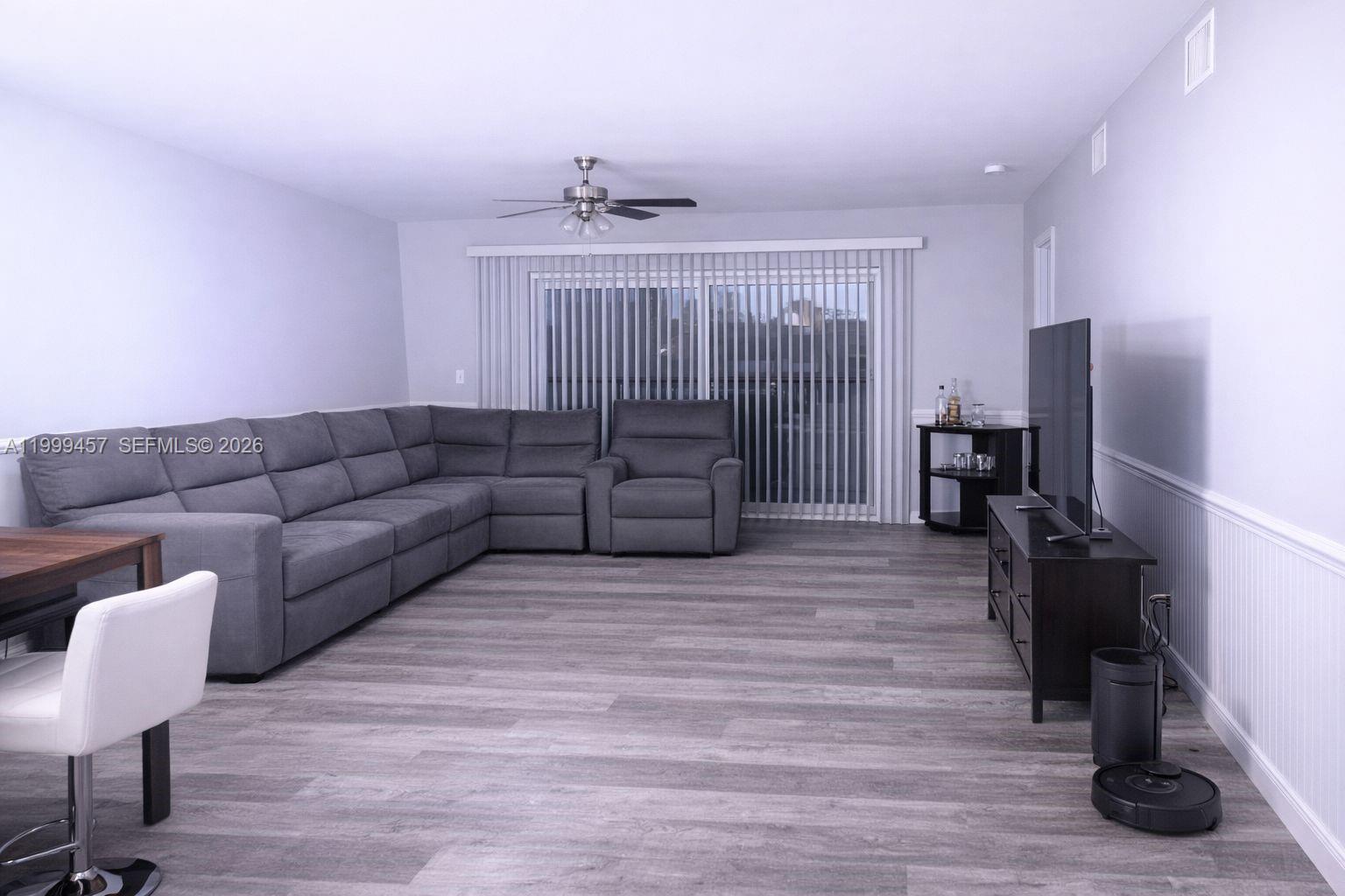 A living room features a large gray sectional sofa, wood-look flooring, and a television console — 2420 SW 81st Ave # 403, Davie FL 33324, DAVIE, FL