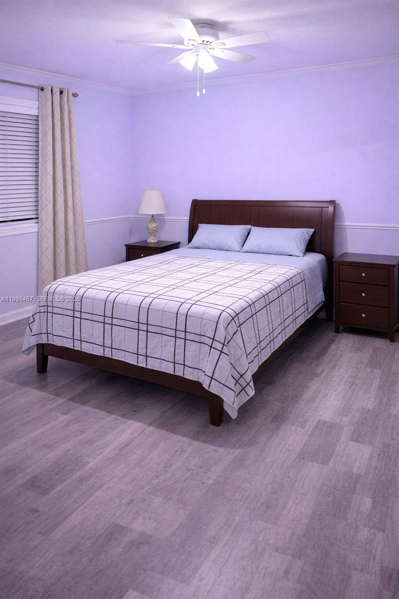 A bedroom features a bed with a plaid comforter, two nightstands, and light purple walls — 2420 SW 81st Ave # 403, Davie FL 33324, DAVIE, FL