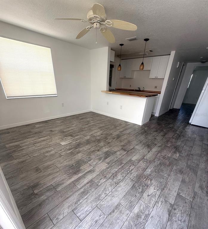 An open-concept living area features wood-look tile flooring, a ceiling fan, and a kitchen pass-through — 4929 FILNER STREET, NEW PORT RICHEY, FL