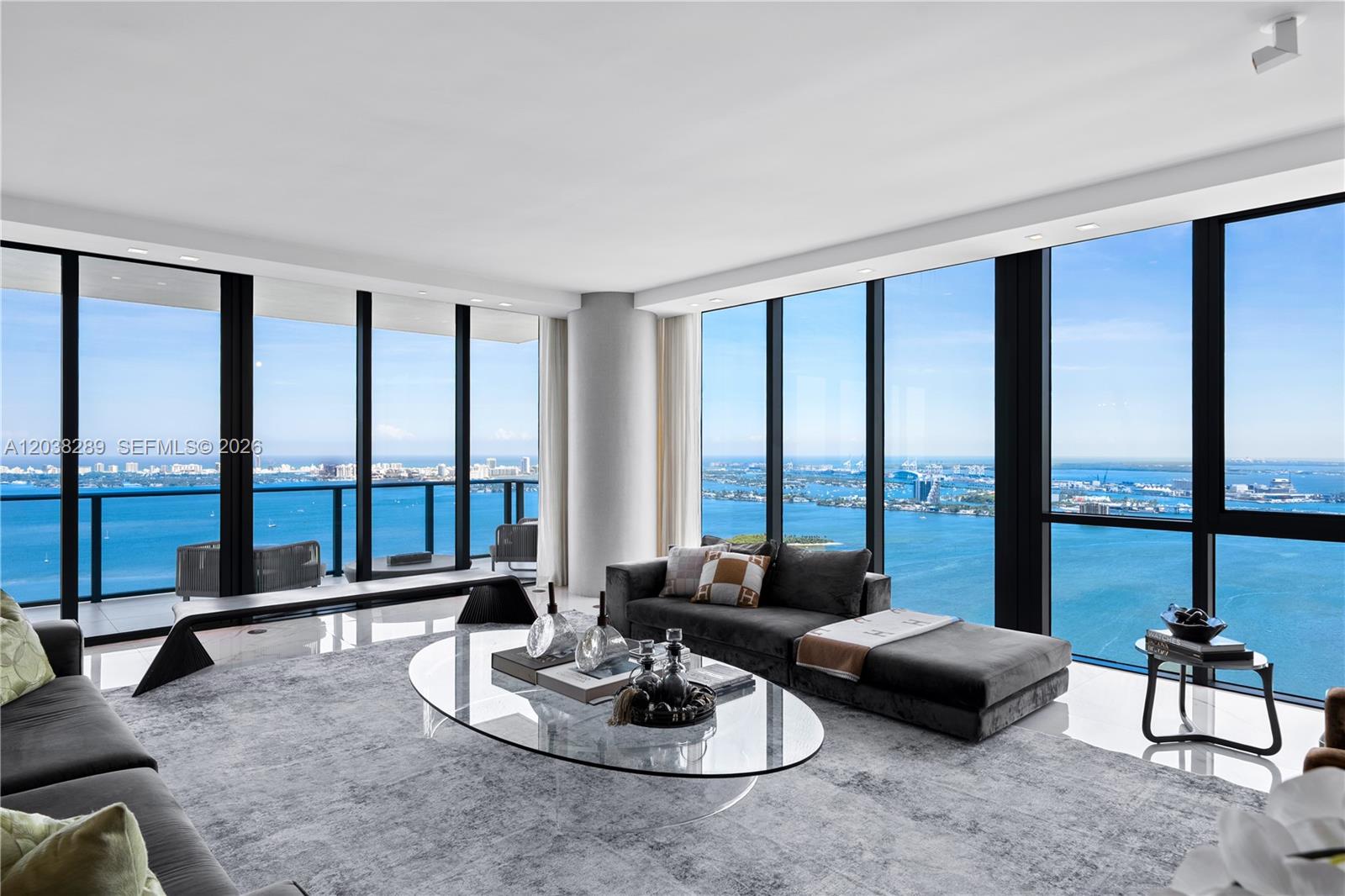 A modern living room features floor-to-ceiling windows with expansive ocean and city skyline views — 3131 NE 7th Ave, Miami FL 33137, MIAMI, FL