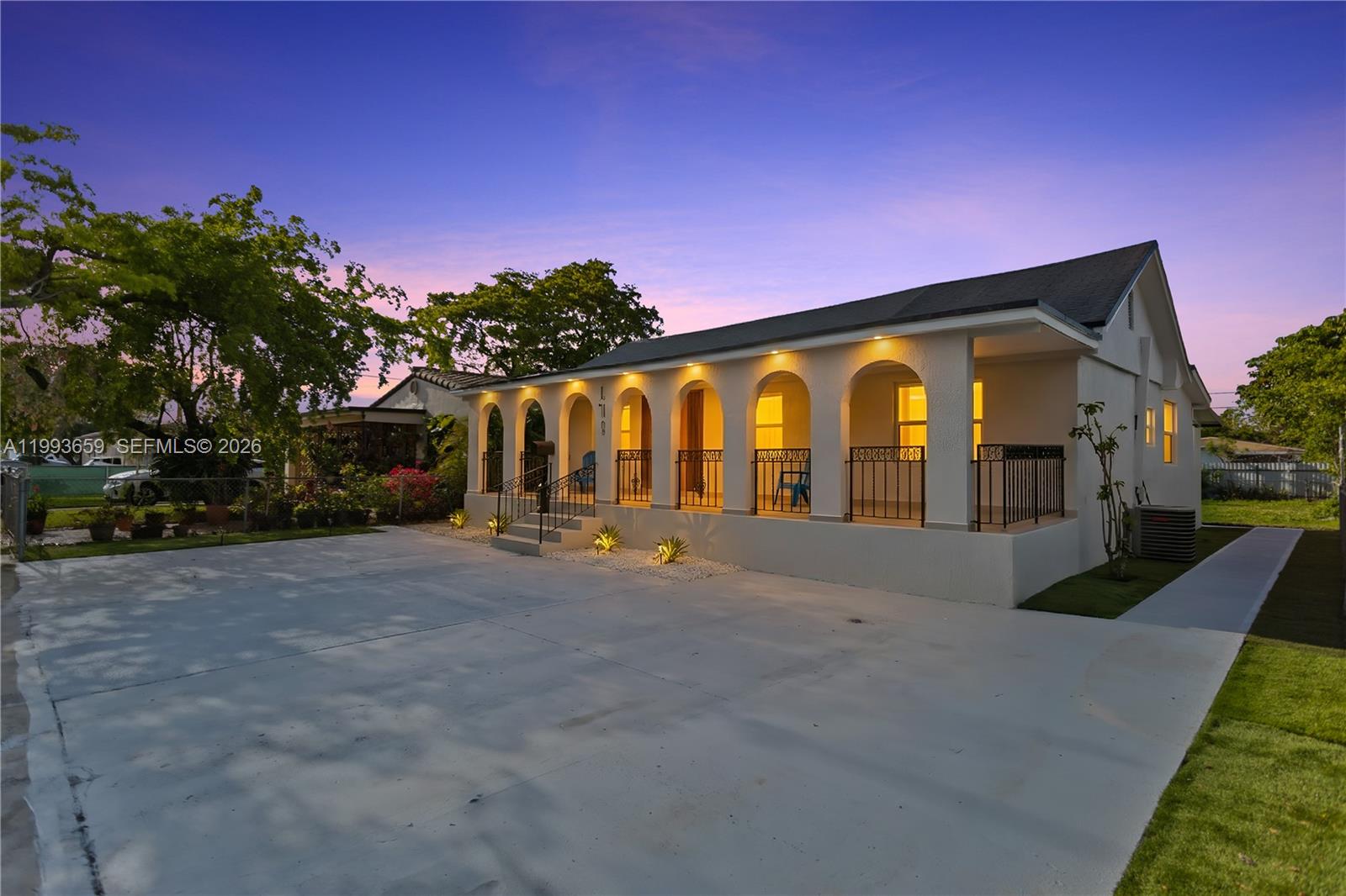 A single-story house with a covered arched porch and a large concrete driveway at dusk — 171 W 13th St, Hialeah FL 33010, HIALEAH, FL