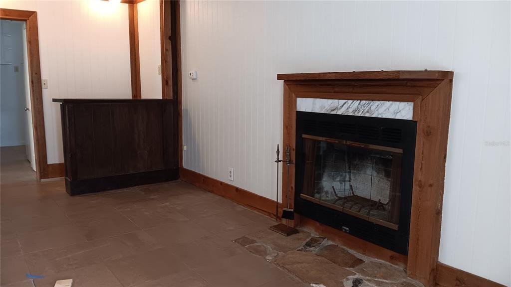 A room with tile flooring, a sliding glass door with vertical blinds, and wood trim — 4840 19TH STREET N, ST PETERSBURG, FL