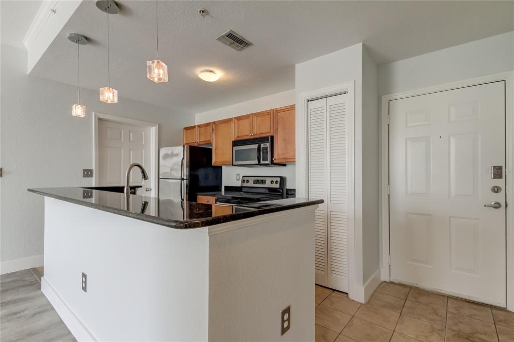 A kitchen features a breakfast bar with black countertops, light wood cabinets, and tile flooring — 700 S HARBOUR ISLAND BOULEVARD UNIT 309, TAMPA, FL