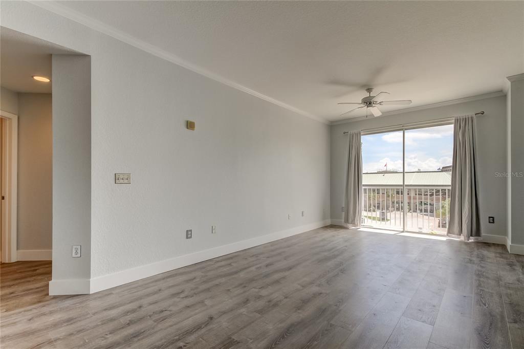 An empty living room with light gray walls, wood-look flooring, and a sliding glass door — 700 S HARBOUR ISLAND BOULEVARD UNIT 309, TAMPA, FL