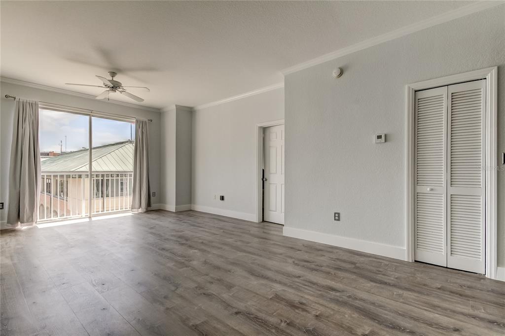 An empty room with wood-look flooring, a ceiling fan, a closet, and a sliding glass door — 700 S HARBOUR ISLAND BOULEVARD UNIT 309, TAMPA, FL