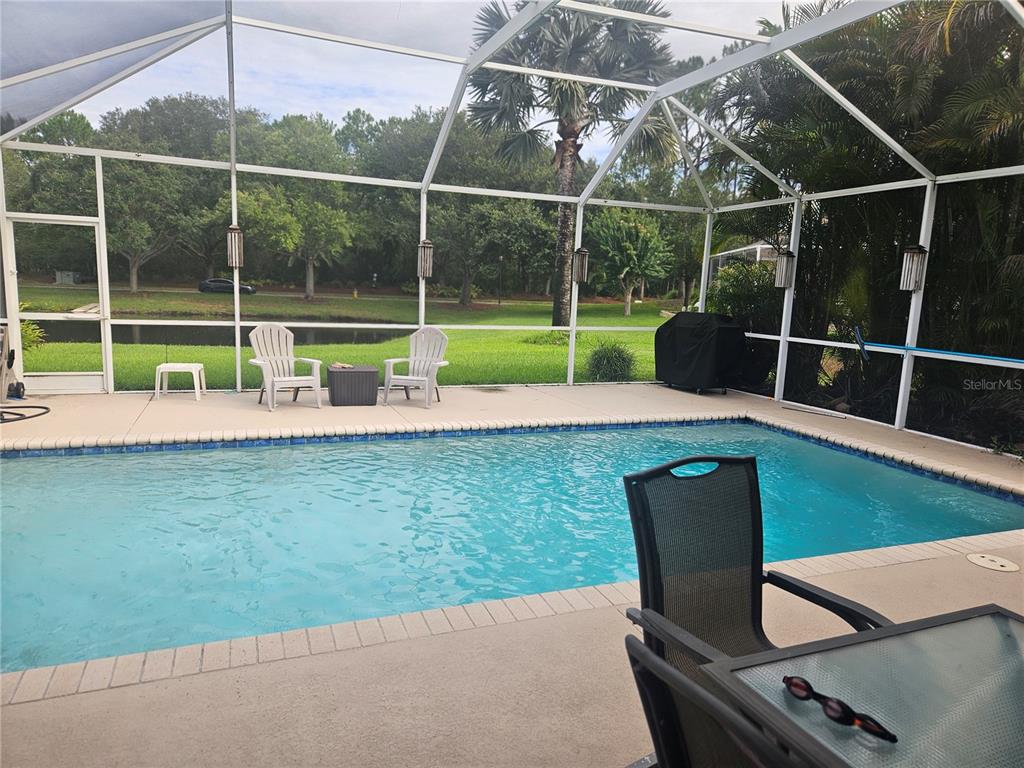 A living room with a glass coffee table, patterned sofa, chaise lounge, and sliding glass doors — 14510 CORKWOOD DRIVE, TAMPA, FL