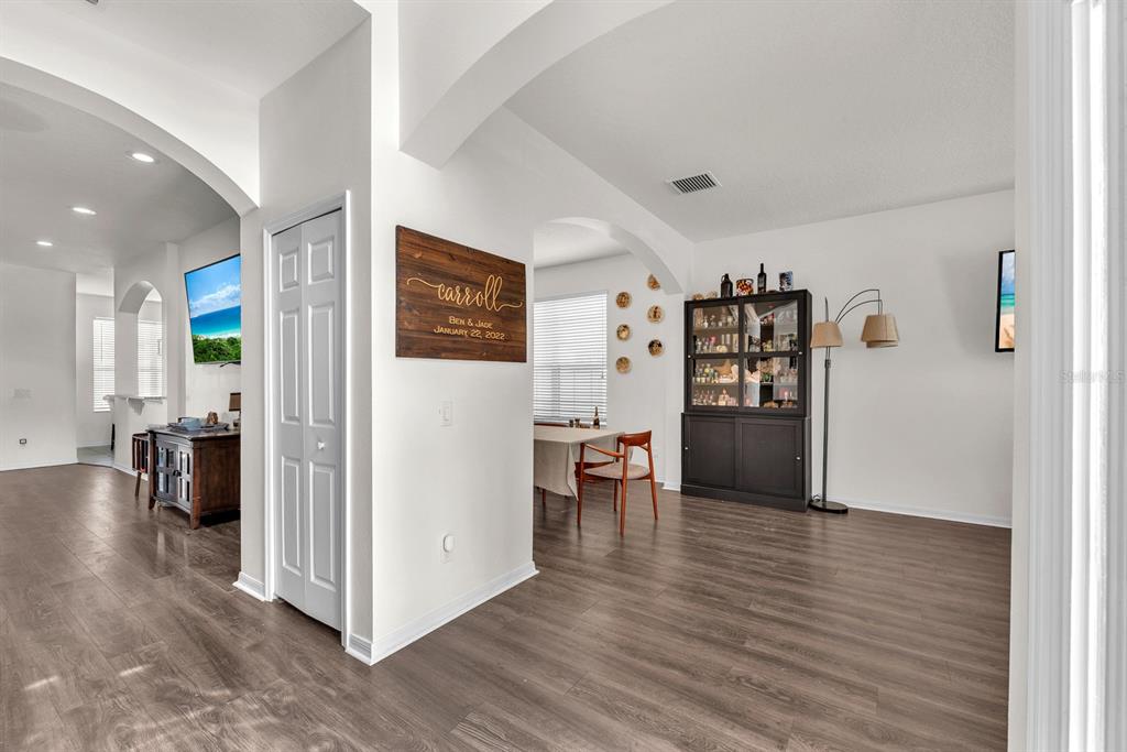 A dining area with wood flooring, a dark display cabinet, and a wall-mounted family sign — 9625 BATON ROUGE LANE, LAND O LAKES, FL