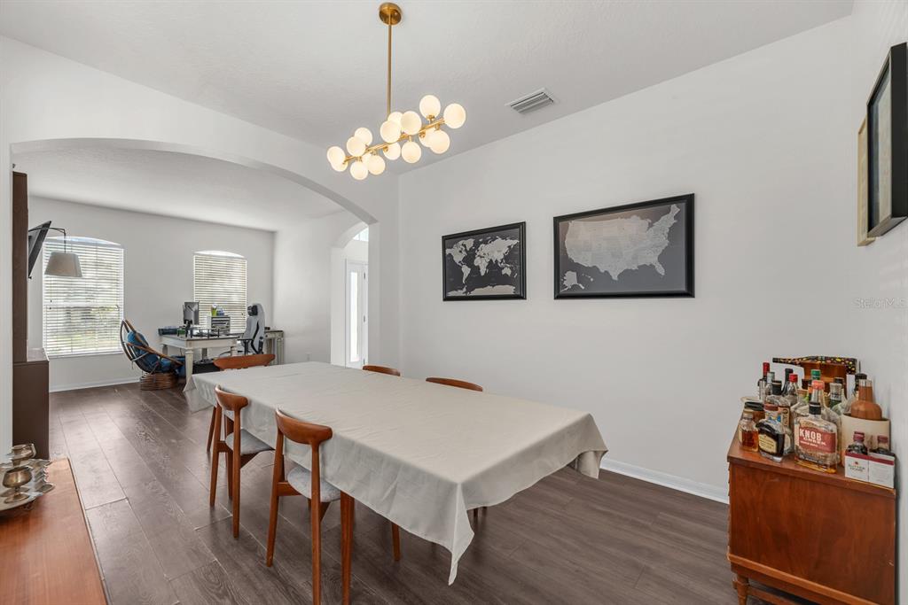 A dining room with a long table, mid-century chairs, a bar cabinet, and wall maps — 9625 BATON ROUGE LANE, LAND O LAKES, FL