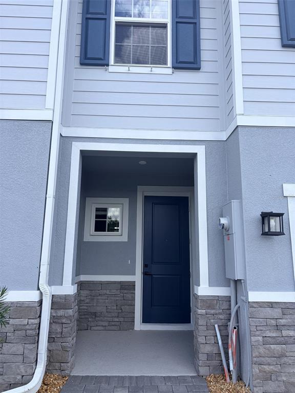 The exterior of a house features a blue front door, stone siding, and a window — 12314 AMBER CREEK CIRCLE, BRADENTON, FL