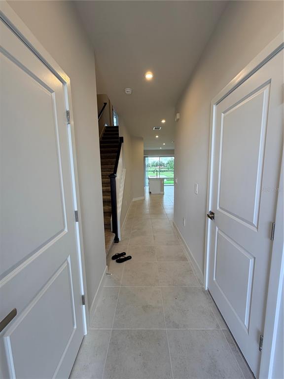 A hallway with tile flooring leads past a staircase to an open kitchen area — 12314 AMBER CREEK CIRCLE, BRADENTON, FL