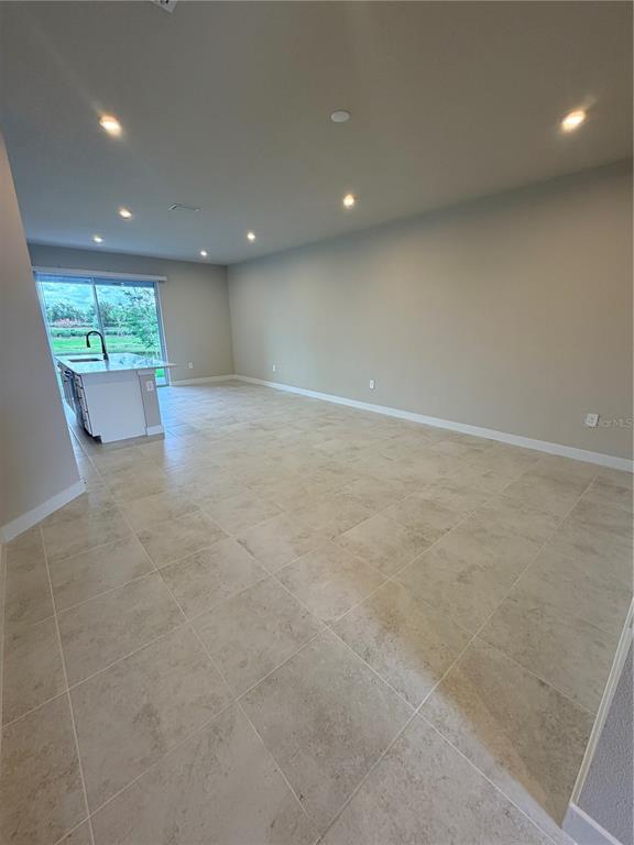 An open-concept living area features light-colored tile flooring, recessed lighting, and a kitchen island — 12314 AMBER CREEK CIRCLE, BRADENTON, FL
