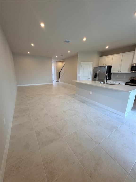 An open-concept kitchen with white cabinets and a quartz island overlooks a tiled living area — 12314 AMBER CREEK CIRCLE, BRADENTON, FL