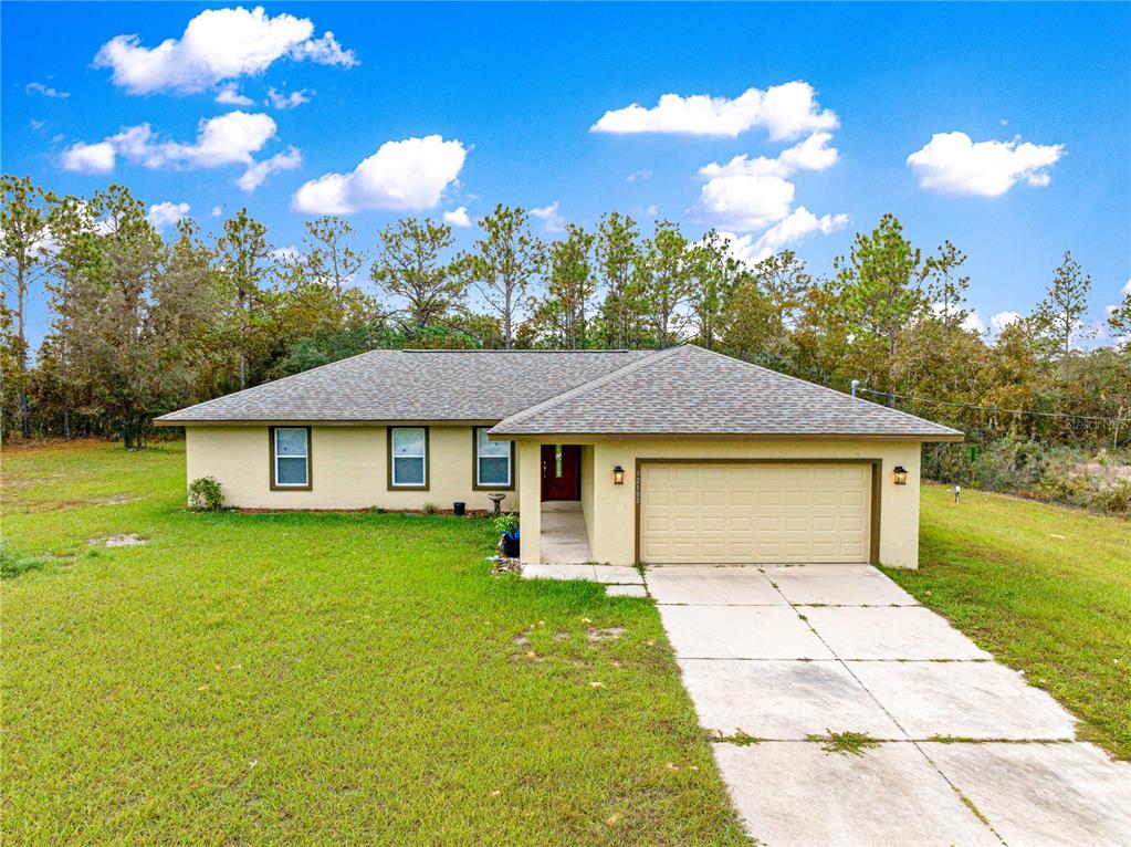 A single-story house with a beige exterior, a two-car garage, and a concrete driveway — 12182 SW 91ST LANE, DUNNELLON, FL