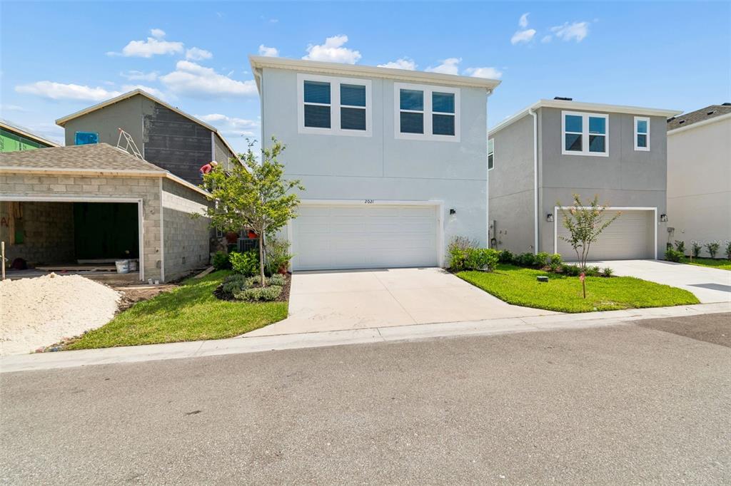 A modern kitchen features a dark blue island, white cabinetry, and light wood-look flooring — 2021 AMELIA BAY PLACE, VALRICO, FL