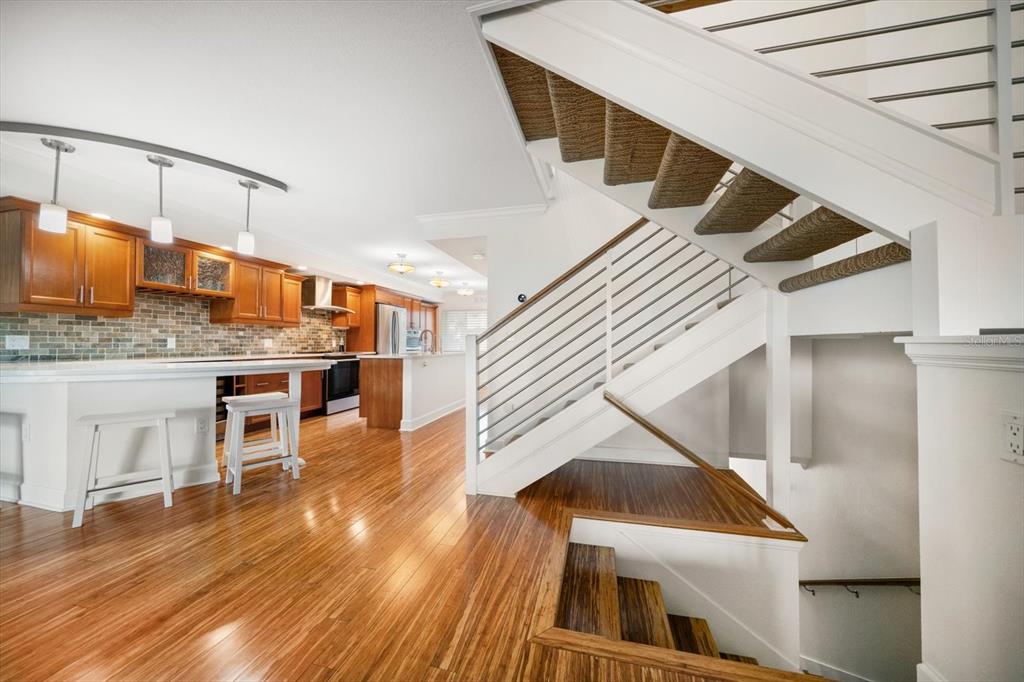 A kitchen with wood cabinets and a staircase with metal railings and woven stair treads — 119 MARINA DEL REY COURT, CLEARWATER BEACH, FL