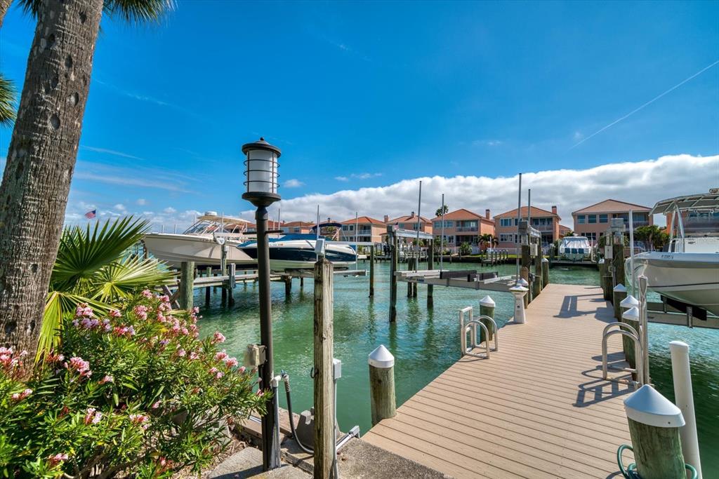 A wooden dock extends into a canal with several boats on lifts and waterfront houses — 119 MARINA DEL REY COURT, CLEARWATER BEACH, FL