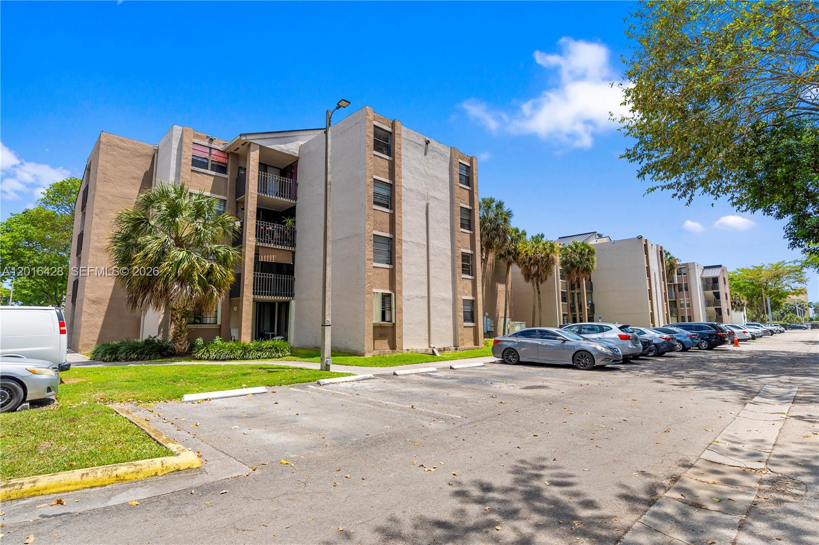 A multi-story apartment building with a parking lot and palm trees in front — 3561 SW 117th Ave # 206, Miami FL 33175, MIAMI, FL