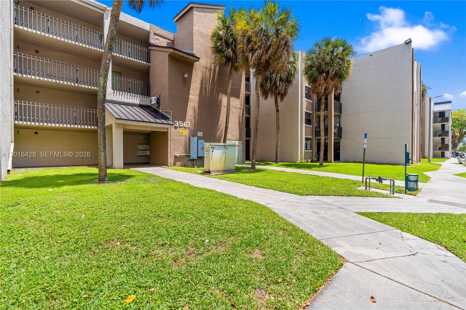 A multi-story apartment building with balconies, palm trees, and a concrete walkway — 3561 SW 117th Ave # 206, Miami FL 33175, MIAMI, FL