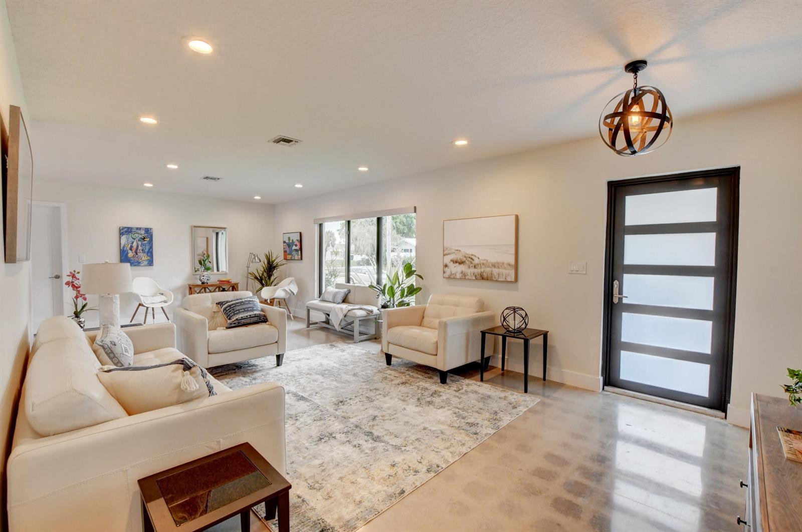 A bright living room features white leather furniture, a patterned area rug, and polished concrete floors — 1440 NW 12th Way, Boca Raton FL 33486, BOCA RATON, FL