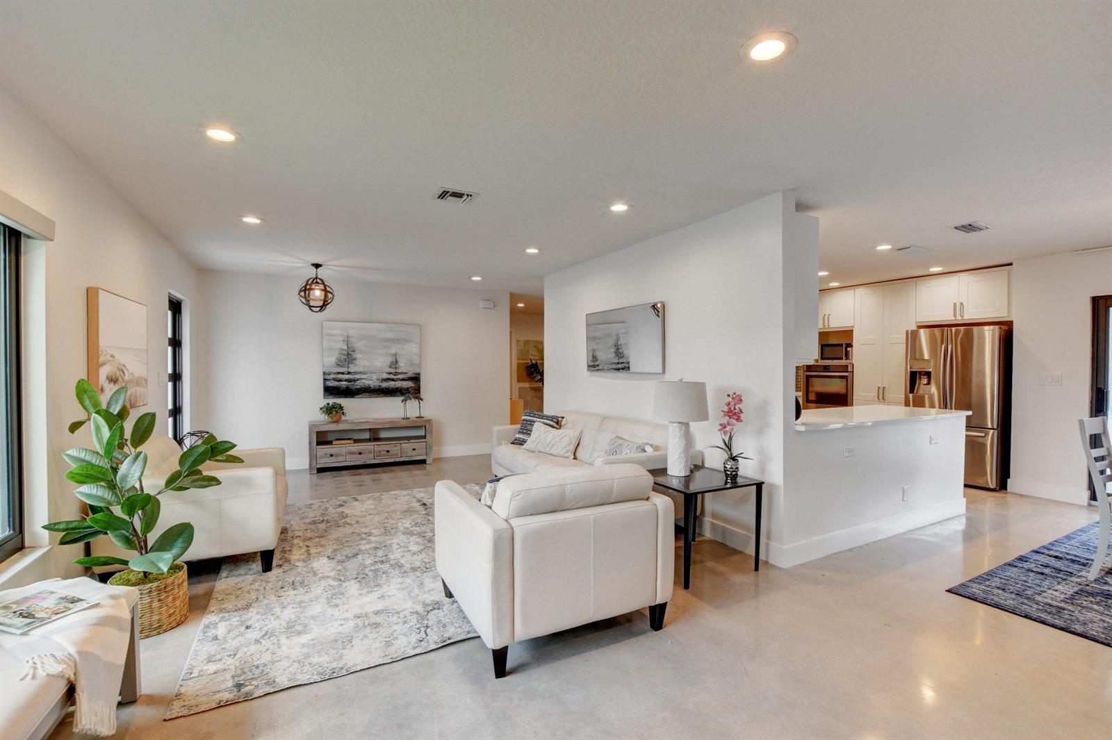 A living room with white furniture and a rug sits adjacent to a modern kitchen — 1440 NW 12th Way, Boca Raton FL 33486, BOCA RATON, FL