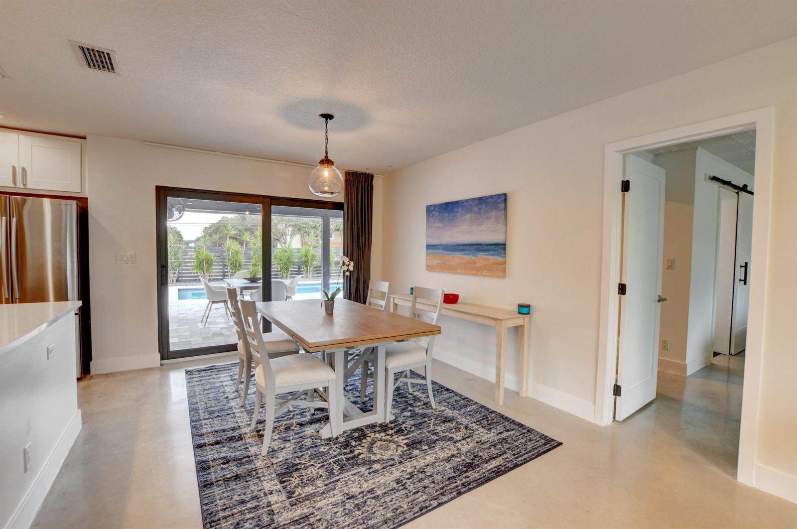 A dining area with a wooden table, chairs, area rug, and sliding doors to a pool — 1440 NW 12th Way, Boca Raton FL 33486, BOCA RATON, FL