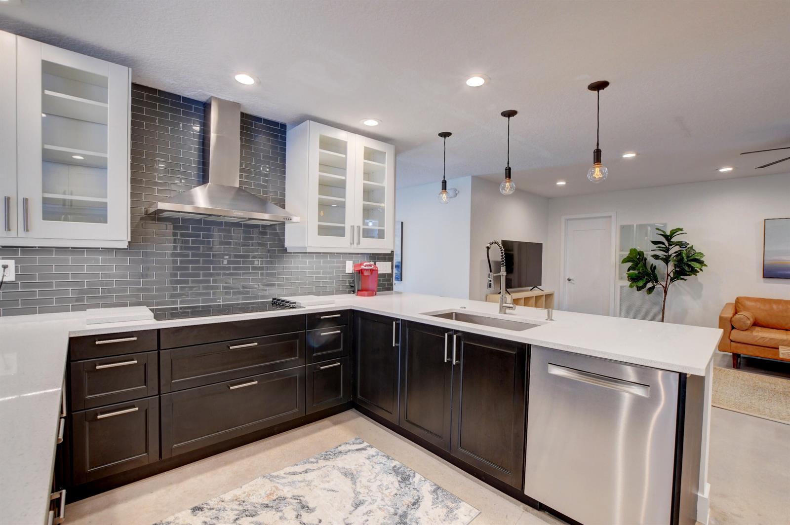 A modern kitchen features dark lower cabinets, white upper cabinets, a gray tile backsplash, and stainless steel appliances — 1440 NW 12th Way, Boca Raton FL 33486, BOCA RATON, FL
