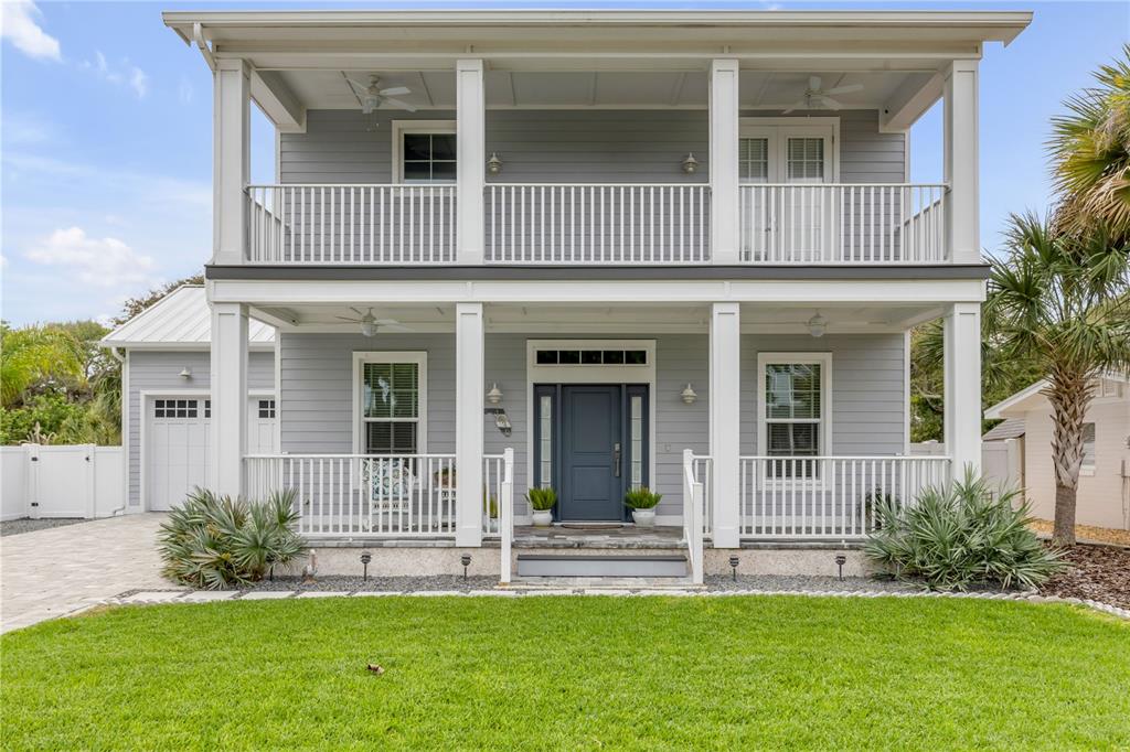 A two-story house with gray siding, a front porch, a balcony, and a white fence — 4636 SAXON DRIVE, NEW SMYRNA BEACH, FL