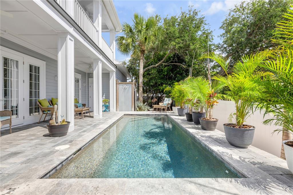 A narrow rectangular swimming pool sits on a stone patio beside a two-story house — 4636 SAXON DRIVE, NEW SMYRNA BEACH, FL