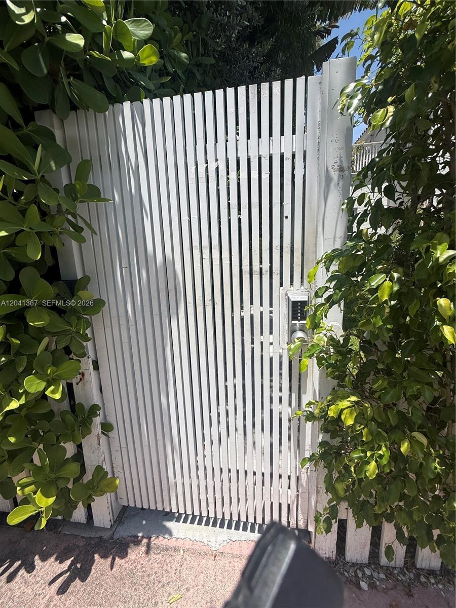 A white vertical-slat wooden gate features a digital keypad lock and is flanked by greenery — 912 Euclid Ave, Miami Beach FL 33139, MIAMI BEACH, FL