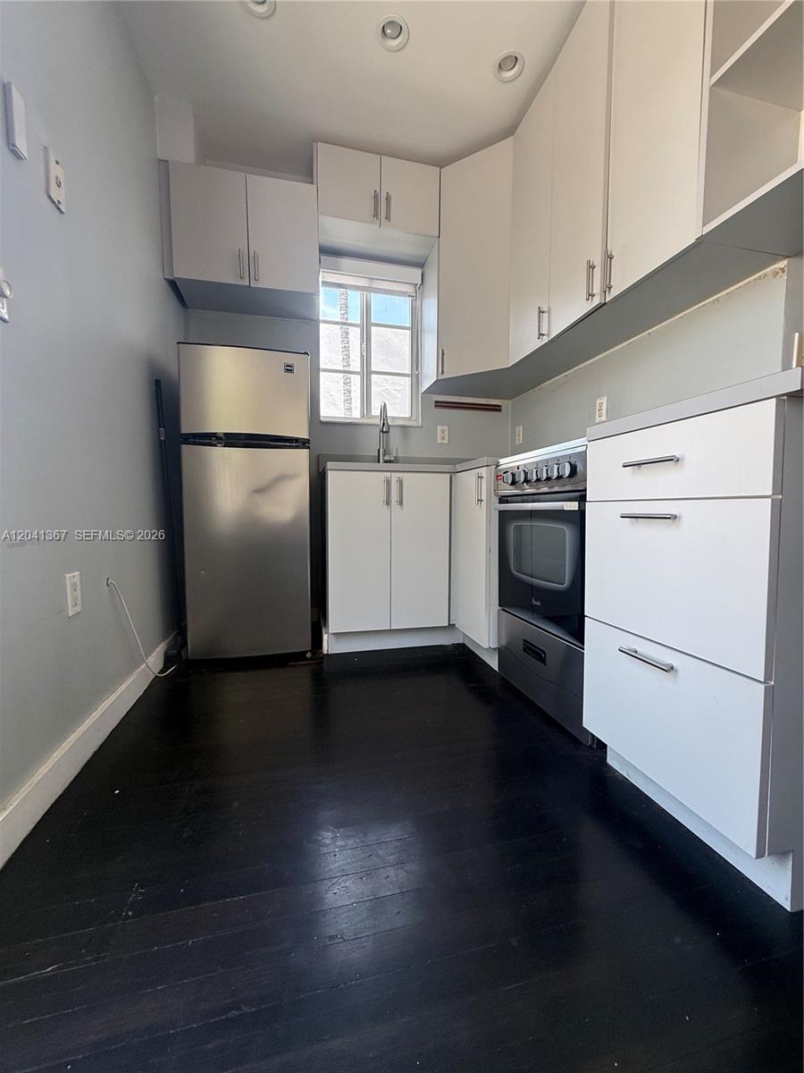 A small kitchen features white cabinets, stainless steel appliances, and dark hardwood flooring — 912 Euclid Ave, Miami Beach FL 33139, MIAMI BEACH, FL