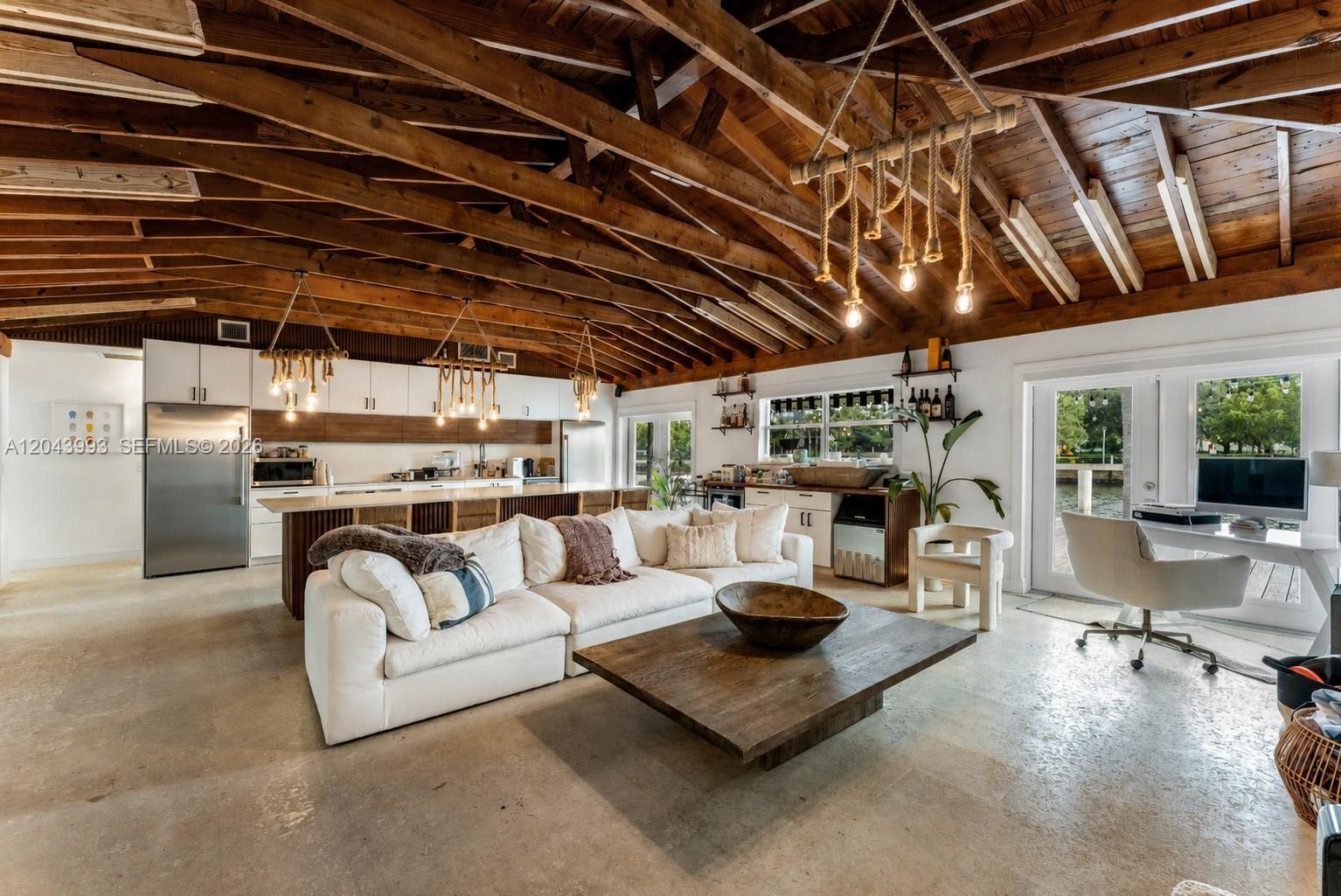 An open-concept living room and kitchen feature a vaulted wood-beam ceiling and concrete floors — 1110 NW North River Dr, Miami FL 33136, MIAMI, FL