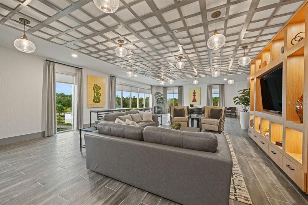 A spacious lounge features a coffered ceiling, gray tile flooring, and built-in wooden shelving — 6000 PARADISO GRANDE BOULEVARD UNIT B2, ORLANDO, FL